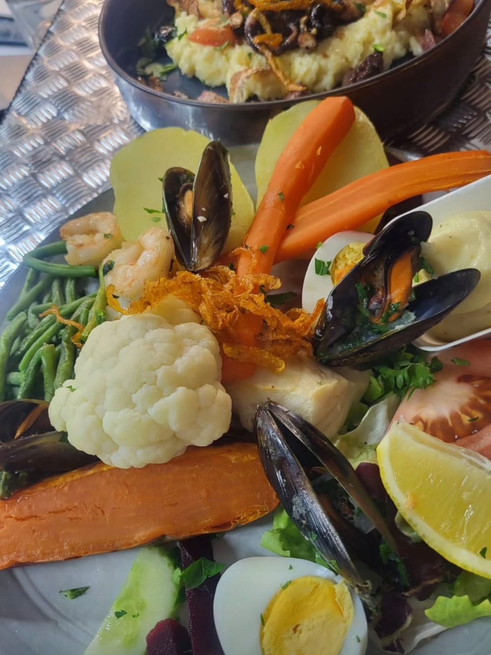 Une assiette d'aïoli : poisson, moules, crevettes, œuf, carotte, chou-fleur, haricots verts et patate douce